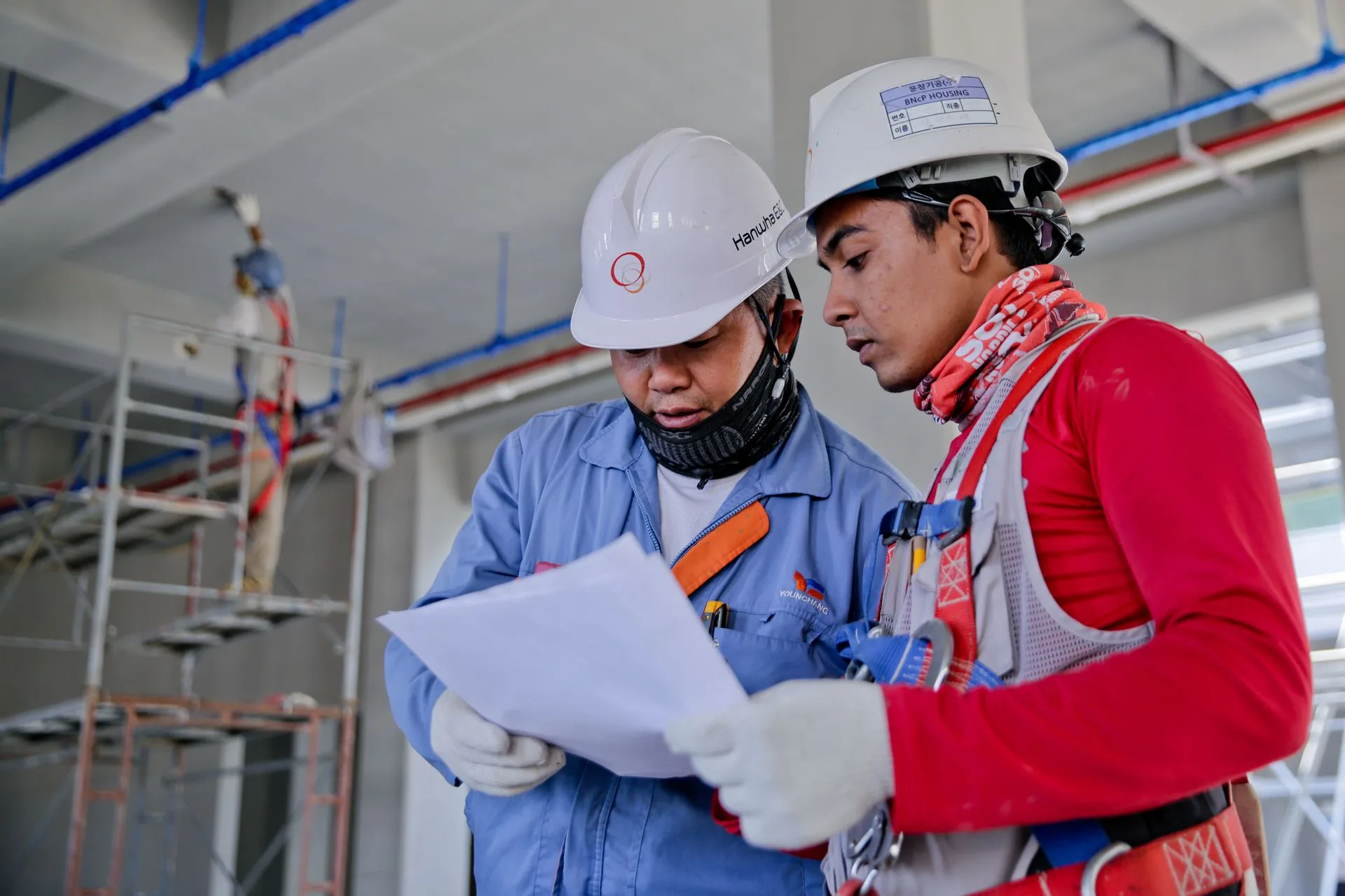 Two construction workers reviewing plans inside a building